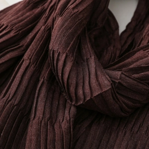 Detailed macro view of dark brown textured scarf with vertical pleated design