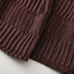 Detailed macro shot of deep brown crinkled fabric texture with vertical pleats