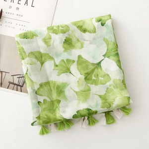 Detail of green ginkgo leaf print scarf with tassels on a white background