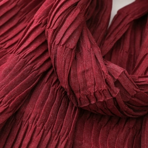 Macro shot showing deep red pleated fabric texture on soft autumn winter scarf