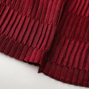 Macro detail of dark red pleated fabric with fine textured ridges and soft elastic structure
