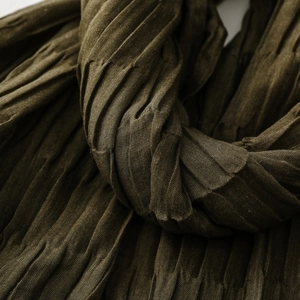 Macro detail of textured dark olive pleated scarf showing deep wrinkle fabric patterns