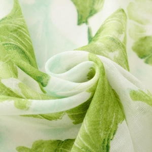 Macro detail of breathable fabric featuring green ginkgo leaves and fine texture