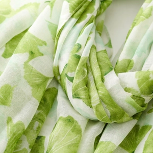 Detailed texture of green ginkgo leaf print on lightweight bohemian ivory scarf fabric
