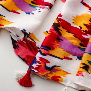 Close-up of vibrant graffiti print scarf showing soft texture and red fringe tassels