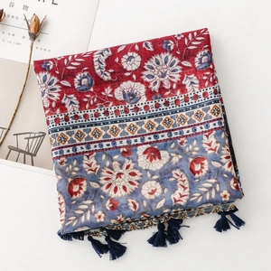 Detail of bohemian scarf with floral prints and navy tassels on a white background