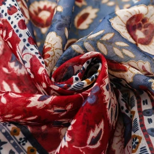 Macro view of ethnic floral print silk scarf showing soft fabric texture and fringe details
