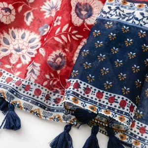 Detail of bohemian scarf with ethnic floral prints and handmade navy blue fringe tassels