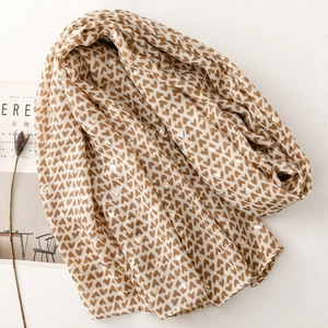 Detail of soft satin scarf featuring brown and gold foil heart prints with artistic texture
