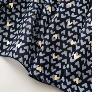 Close-up of navy satin scarf showing gold foil heart prints and textured fabric details