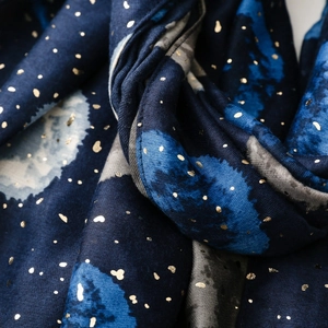 Détail d'écharpe en coton et lin bleu avec imprimé lune dorée et texture tissée