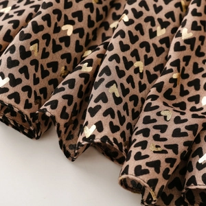 Detail of satin scarf fabric with heart patterns and gold foil prints in brown