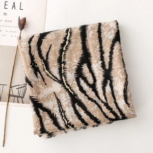Detailed view of camel tiger print shawl with soft fringed edges on a minimalist background