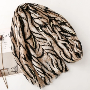 Detailed view of beige scarf with zebra print, gold accents, and frayed edges