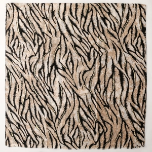 Detail of soft linen-feel scarf featuring golden zebra print with frayed edges and earth tones