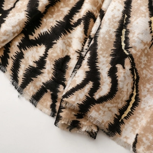 Detail view of cotton-linen feel scarf with gold zebra print and frayed edges