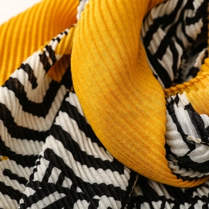 Detailed view of yellow and zebra stripe pleated fabric with fine micro-fold texture