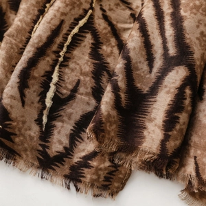 Detail of soft tiger print scarf with metallic gold thread and delicate fringed edges