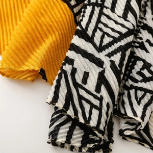 Macro detail of pleated yellow scarf with black and white geometric zebra patterns