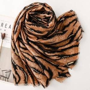 Detail shot of animal print scarf with golden tiger stripes and fringe edges