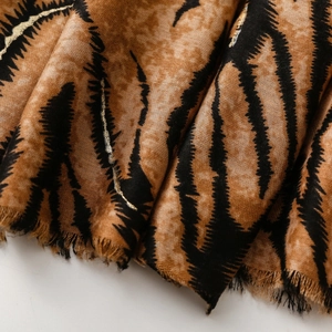 Macro detail of soft animal print scarf with gold glitter lines and frayed edges