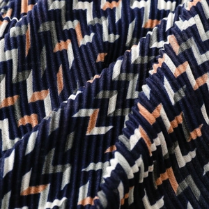 Macro detail of navy and orange geometric pleated scarf showing fine fabric texture