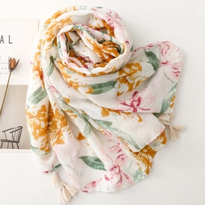 Detail of floral cotton linen scarf with soft orange and pink blossoms and cream tassels