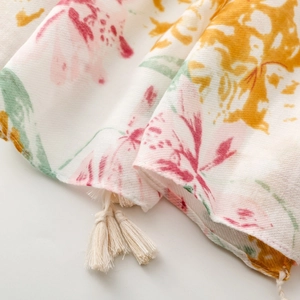 Detailed close-up of floral print cotton-linen scarf with elegant tassel fringe edges