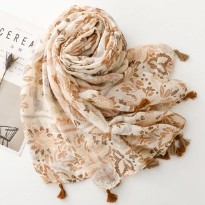 Detail of bohemian leaf print scarf with brown tassels on a minimalist magazine layout