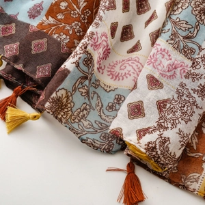 Détail d'une écharpe bohème en coton et lin avec motifs paisley et franges à pompons