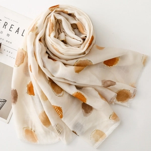 Detail of thin lightweight scarf with gold foil polka dots on cream fabric with frayed edges