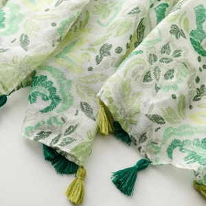 Detailed view of lightweight floral scarf with layered fabric and green tassel accents