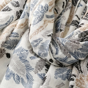 Detailed view of lightweight scarf with blue and brown feather geometric patterns