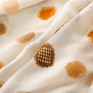Detail of lightweight scarf fabric with bronze polka dots and metallic gold foil stamping