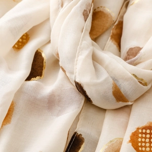 Detailed macro view of thin scarf fabric with gold foil polka dots and soft texture
