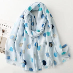 Detail of light blue scarf featuring metallic gold polka dots and soft fringe edges