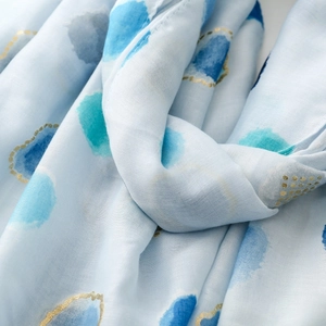 Close-up of light blue scarf featuring watercolor polka dots and gold foil details