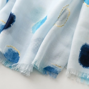Close-up of light blue scarf with navy watercolor dots and gold foil accents