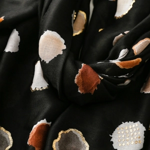 Detailed view of black scarf featuring colorful polka dots and golden embroidery texture