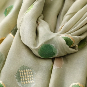 Macro detail of mint green scarf with gold foil polka dots and soft cotton-linen texture