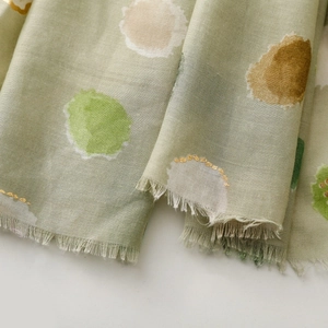 Detail of lightweight green scarf with colorful dots and fine tassel edges texture