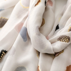 Macro detail of scarf showing gold dots and artistic abstract patterns on soft fabric