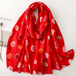 Detail of red scarf with colorful polka dots and artistic frayed edges on white background