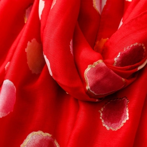 Detailed texture of red scarf with gold foil polka dots and soft flowing fabric