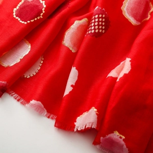 Detail of red scarf with gold-foiled polka dots and soft fringe edges