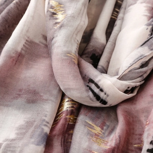 Macro detail of scarf showing golden foil stamping on purple gradient chiffon fabric