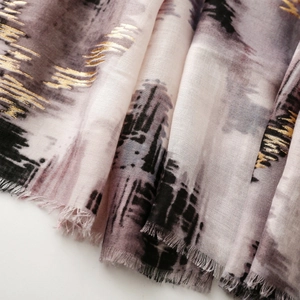 Close-up of landscape ink print scarf with gold foil details and frayed edges