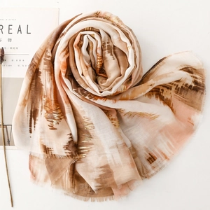 Macro view of gold foil details and abstract ink print on a lightweight silk scarf