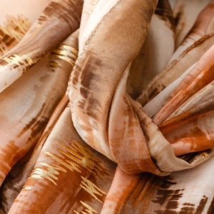 Detailed close-up of abstract ink-wash pattern and gold foil accents on a silk scarf