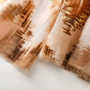 Detailed view of bronze and khaki scarf with gold foil accents and fringe edges